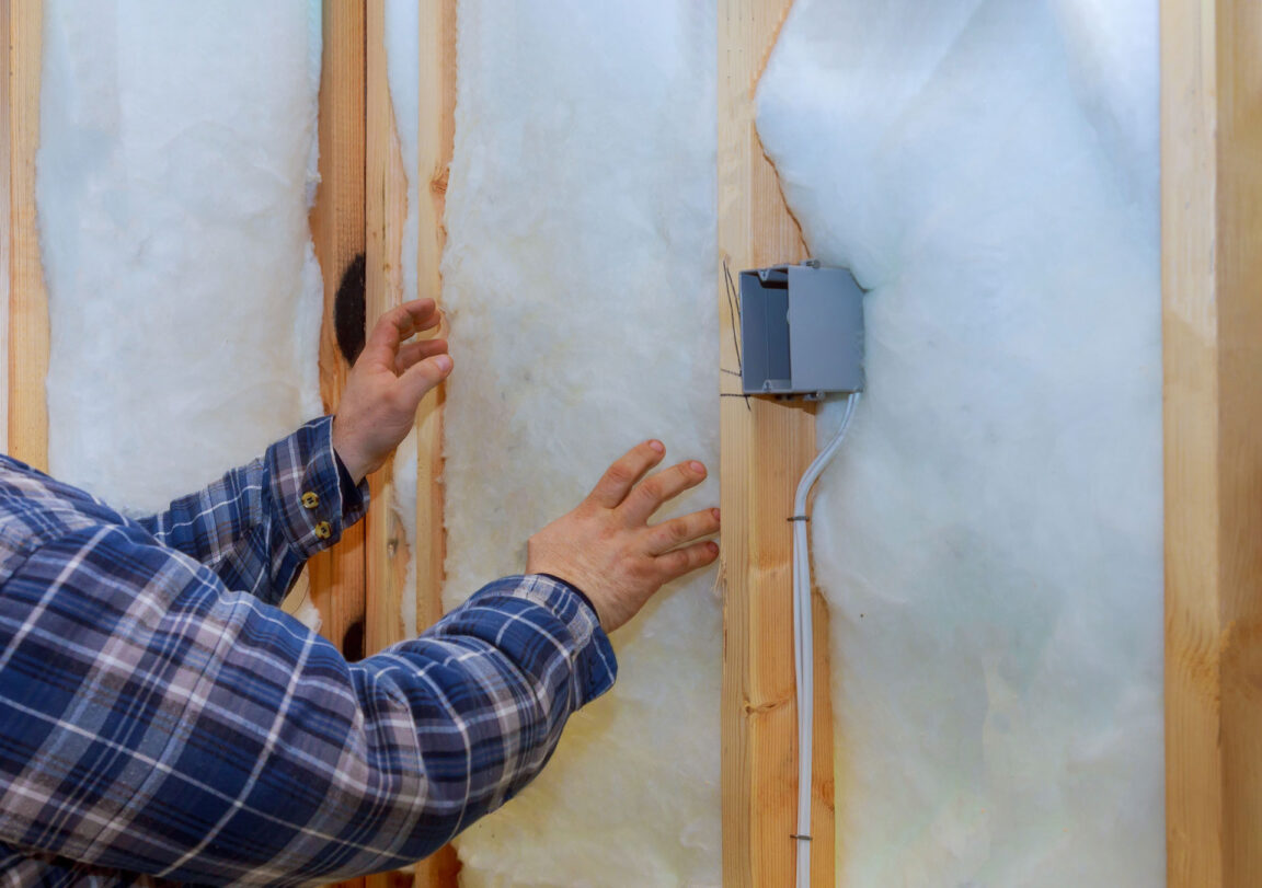 man installing batt fiberglass insulation