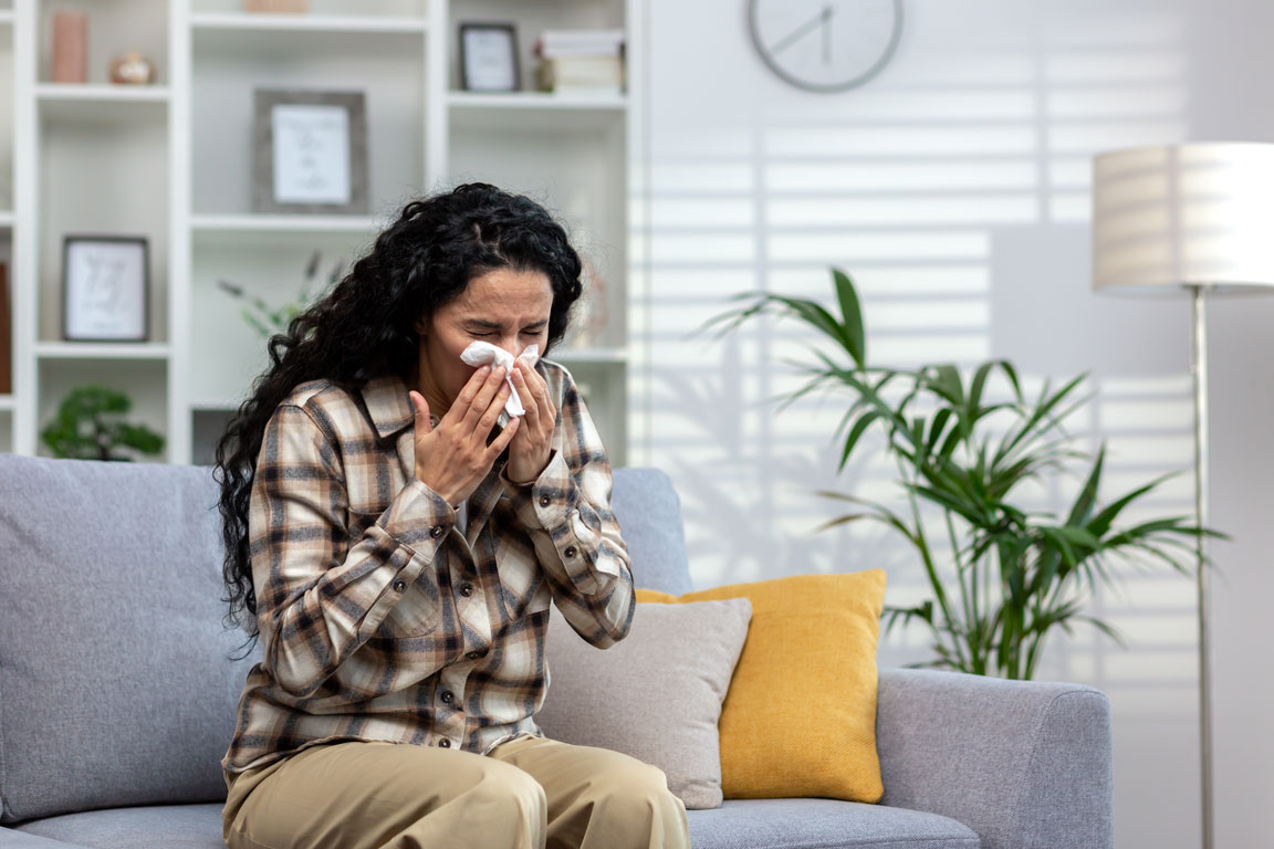 woman sneezing on couch