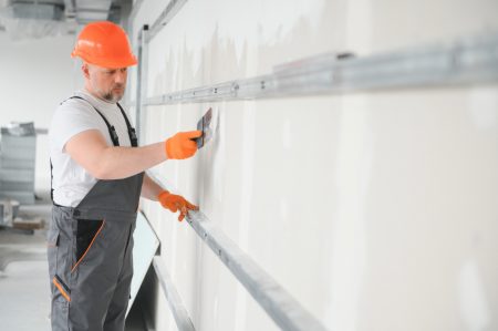 Construction worker installing drywall